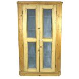 A large early 20th century pine corner cupboard, with double mesh panelled doors, blue interior with