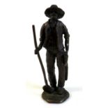 A bronze sculpture of a miner, the man dressed in working clothes carrying a pickaxe in one hand and