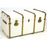 An early 20th century travelling trunk, white painted canvas and wooden bound, leather carrying