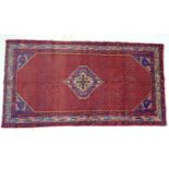 A hand knotted woollen Arak rug, with central blue and caucasian medallion on a red ground, and a