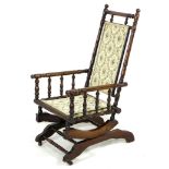 An American rocking chair, turned spindle frame, metal sprung rocking action, floral embroidered