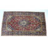 A Kashan rug with red ground, central dark blue and cream floral medallion with pendant anchors,