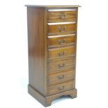 A reproduction George III style semainier, being a narrow chest of seven drawers, raised on