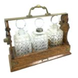 A Victorian oak tantalus, with three clear glass hobnail cut decanters.