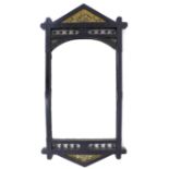 An Arts & Crafts ebonised mahogany wall mirror, with decorative carved frame, triangular panels to