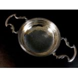 A George V silver lemon strainer, with twin handles, fine bead rim and pierced bowl, Goldsmiths &