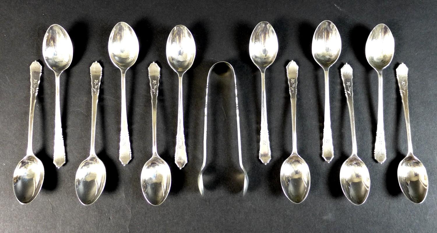 An Elizabeth II silver set of twelve teaspoons and pair of sugar nips, decorated with engraved
