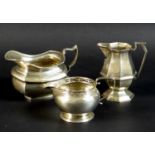 A group of three silver jugs comprising a jug of squat rectangular form with shaped scroll handle,