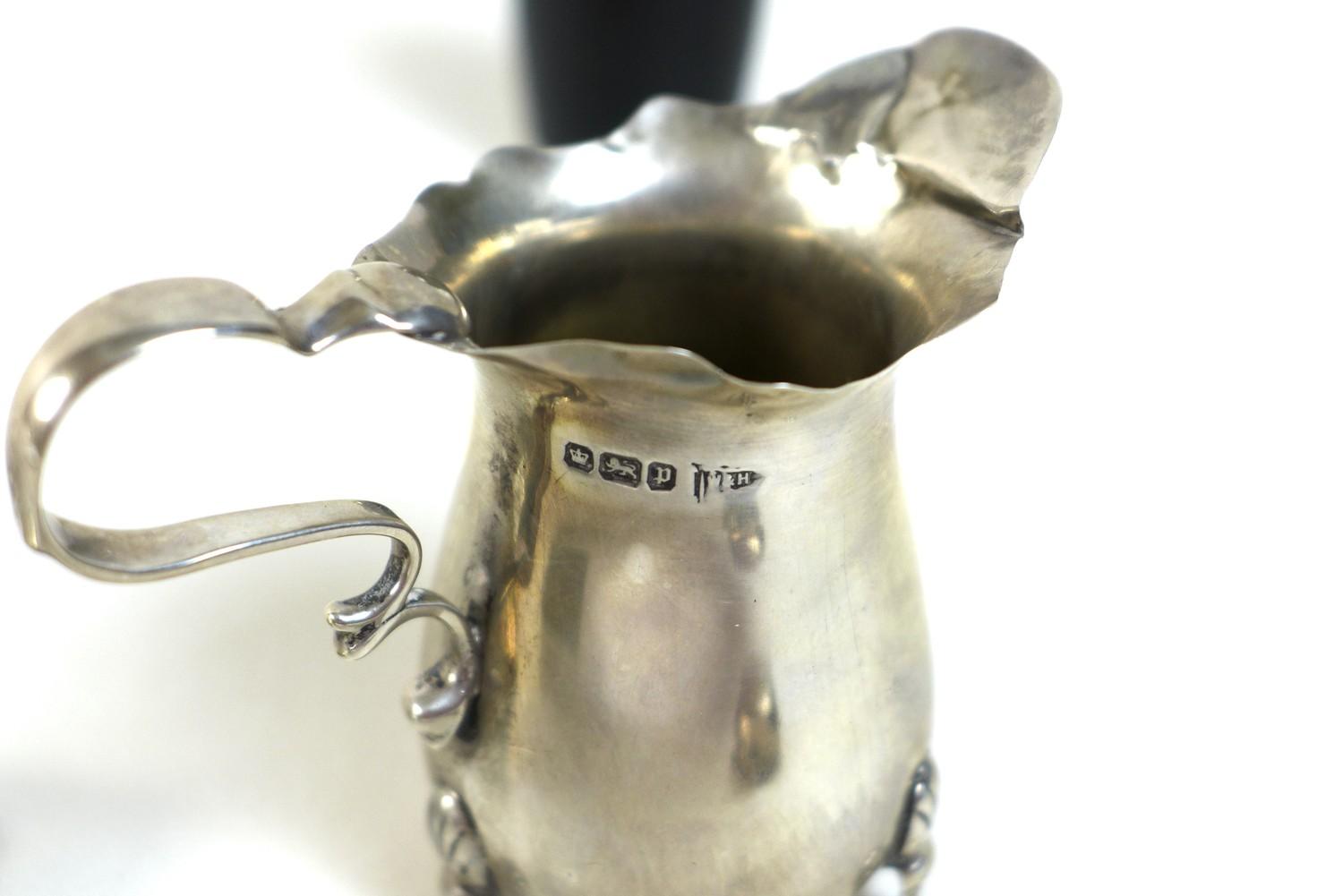 A silver cream jug raised on three pad feet, Walker and Hall, Sheffield 1907, 1.25toz, 7.2 by 3.6 by - Image 6 of 6