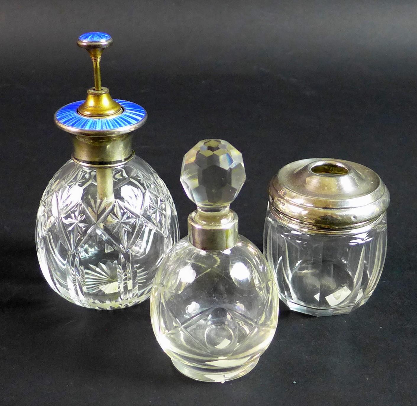 Three silver and cut glass dressing table items, comprising a silver and enamel topped atomiser,