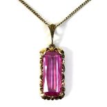 A 14ct gold pink sapphire pendant, the emerald cut pink sapphire 20 by 8mm, with 14ct gold rococo