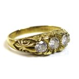 An 18ct gold and diamond three stone ring, the scroll mount set with three similarly sized diamonds,