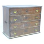 An early 18th century oak chest of four drawers, with brass handles and lock plates, black metal