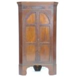 A Victorian mahogany freestanding corner cupboard, twin arched doors opening to reveal three fixed