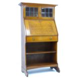 An oak student?s desk, circa 1930, with drop front and glazed cupboard, 79 by 41 by 140cm high.