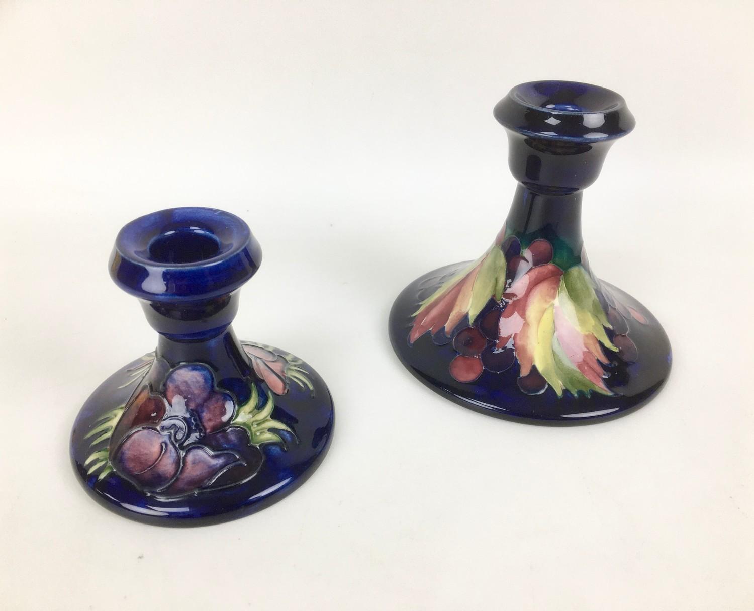 Two Moorcroft pottery candlesticks, comprising one decorated in the leaf and berry pattern, with