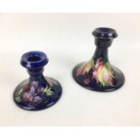 Two Moorcroft pottery candlesticks, comprising one decorated in the leaf and berry pattern, with