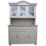 A painted kitchen dresser with arched pediment to the glazed three door cupboard above shelf and