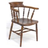 A 19th century burr oak and elm smoker's bow armchair, with shaped arms supported on turned