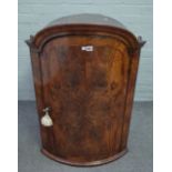 A mid-18th century figured walnut bowfront hanging corner cupboard,