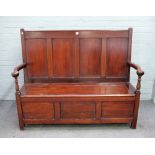 An Arts & Crafts mahogany box seat settle, the four panelled back over open arms,