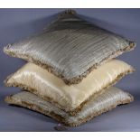 A group of three modern part silk cream and gold cushions, each 62cm wide.