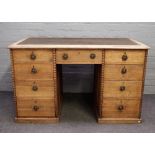An early 20th century bleached oak writing desk with nine drawers about the knee,