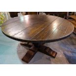 A 20th century oak circular dining table on turned column and 'X' frame base,