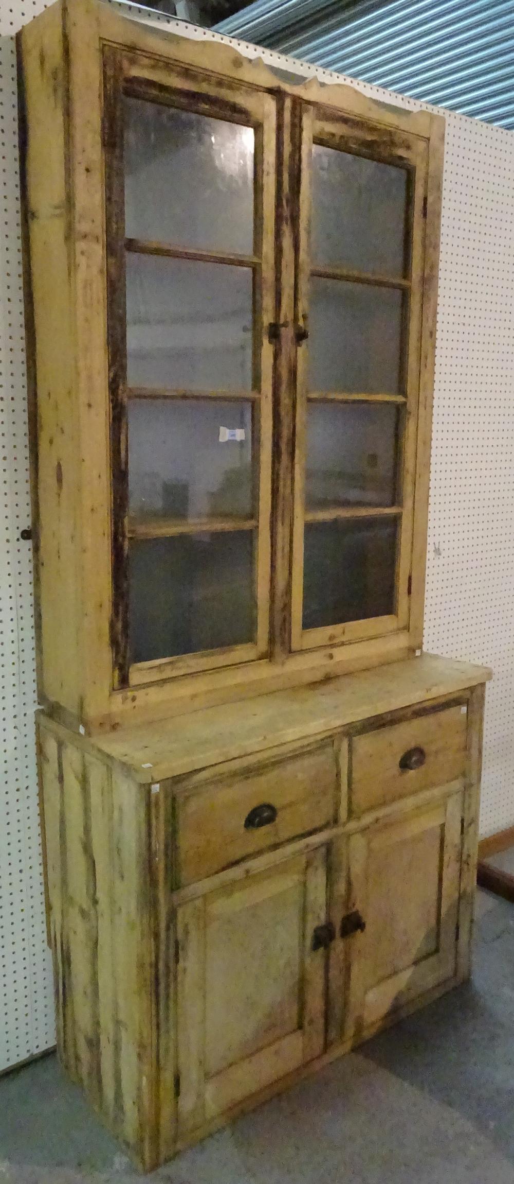 An early 20th century pine dresser with two door glazed top section over two drawer cupboard base,