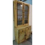 An early 20th century pine dresser with two door glazed top section over two drawer cupboard base,