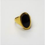 A gold and black onyx oval signet style ring, of slightly curved form unmarked, ring size N,