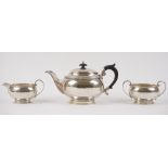 A silver three piece tea set, comprising; a teapot with black fittings,