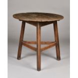 A 19th century oak cricket table, the circular plank top on three rectangular supports,