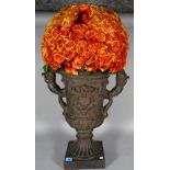 A Victorian style composite faux cast iron twin handled urn with an arrangement of dried orange
