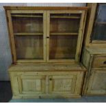 A 20th century pine bookcase with two glazed doors over cupboard base, 130cm wide x 157cm high.
