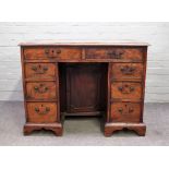 A George III mahogany kneehole desk with eight drawers about the cupboard on bracket feet,