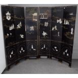 An early 20th century Chinese black lacquer six fold screen decorated in relief with