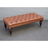 A rectangular brown leather upholstered footstool, on turned mahogany supports,
