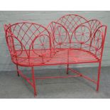 A red painted wrought iron love seat, 110cm wide x 89cm high.