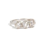 A platinum and diamond set three stone ring, claw set with a row of cushion shaped diamonds,