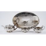 A silver composite three piece tea set, comprising; a teapot, with a wooden handle,