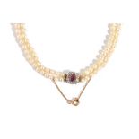 A two row necklace of graduated cultured pearls, on a gold, ruby and diamond set cluster clasp,