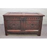 A 17th century oak coffer, with double panel lid and carved double panel front, on stile feet,