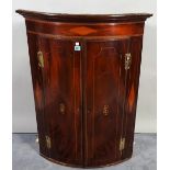 A late George III mahogany inlaid bowfront hanging corner cupboard, 76cm wide x 102cm high.