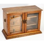 An early 20th century oak table top collector's chest the glazed door enclosing three drawers and