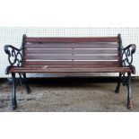 A 20th century black painted cast iron garden bench with scroll ends and wooden slats,