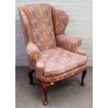 A George I style walnut framed wing back armchair, with bow seat, on scroll capped pad feet,