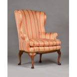 A George I style walnut framed wing back armchair, with bow seat, on scroll capped pad feet,