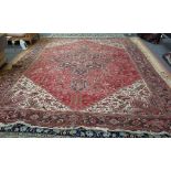 A Heriz carpet, Persian, the washed madder field with a bold angular medallion, ivory spandrels,