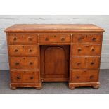 A Victorian pine kneehole writing desk, with nine drawers about the cupboard, on bun feet,